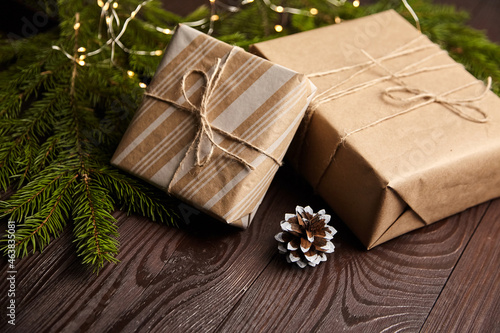 Gift boxes with Christmas light and tree branch with cone on brown wooden © mikeosphoto