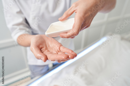 Masseuse pouring massage oil on her hands