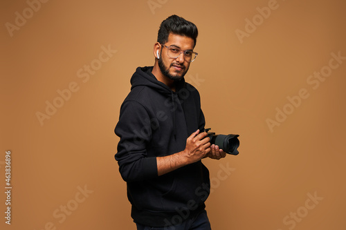 Photography Happy indian photographer in black hoody with proffesional camera on background