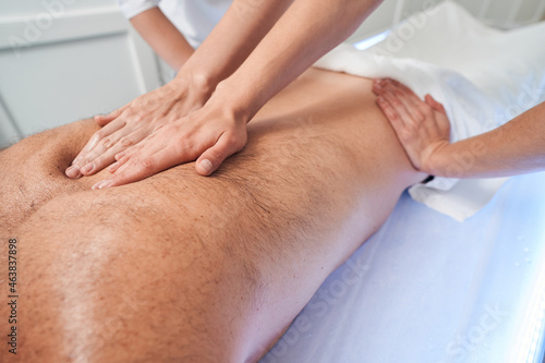 Two masseuses massaging male back in spa salon