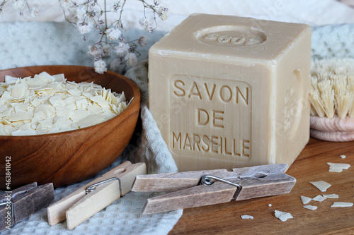 Marseille soap bar named Savon de Marseille in french and grated soap on the cotton towel with clothes pegs and washing brush at home laundry close up. 