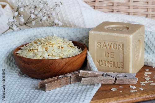 Marseille soap bar named Savon de Marseille in french and grated soap on the cotton towel with clothes pegs and washing brush at home laundry close up. 