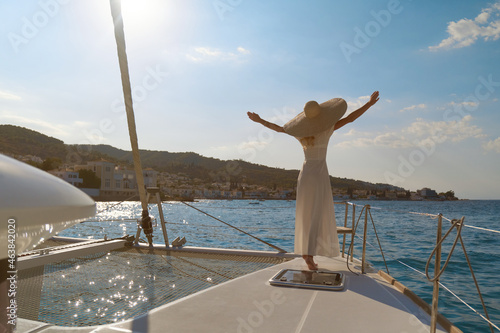 Beautiful woman wearing straw hat and white dress on a yacht enjoys the journey, Spetses, Greece, Europe photo