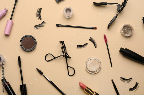 Flat lay composition with eyelash curlers, makeup products and accessories on beige background