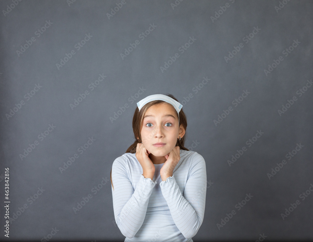 Portrait of a young girl with medical mask on hear head on grey background. Portrait of a young girl with medical mask on hear head on grey background.