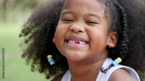 Portrait Little African girl with curls smiling sincerely white teeth looking at camera ,happy cute child has fun. 