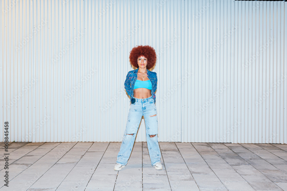 Fashionable woman with Afro hairstyle standing near wall Fashionable woman with Afro hairstyle standing near wall