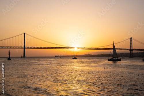 Vivid sky during sunset in a river with a bridge and a sailing boat © carles