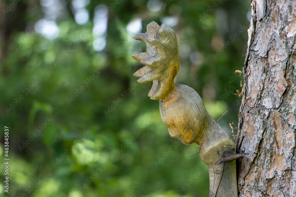 Fototapeta premium Carved human head with antlers attached to a tree trunk