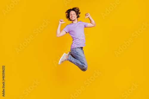 Photo of positive confident man jump direct thumb fingers himself wear casual jeans clothes on yellow background