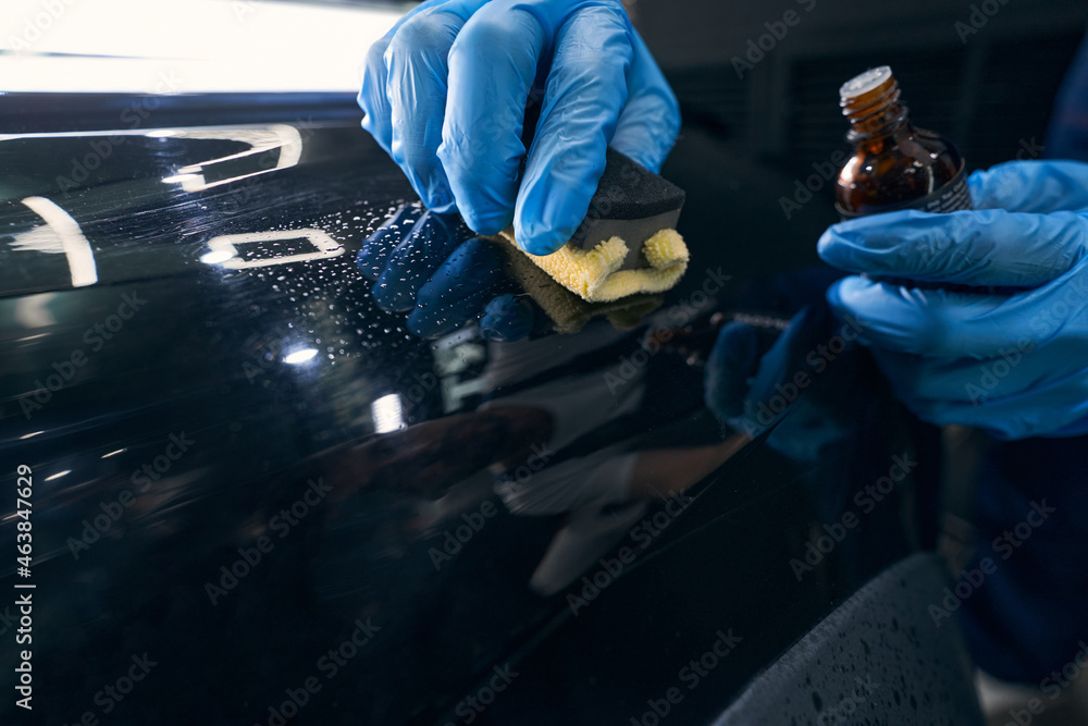 Repairman applying ceramic coating to car surface - obrazy, fototapety, plakaty 