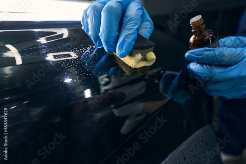 Repairman applying ceramic coating to car surface photo