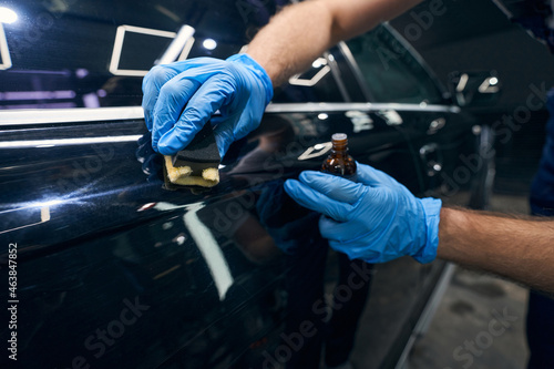Person applying coating on car surface scratches photo