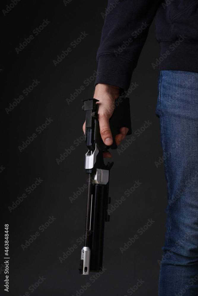 Gun shooting sport. Man holding standard pistol on dark background, closeup Gun shooting sport. Man holding standard pistol on dark background, closeup