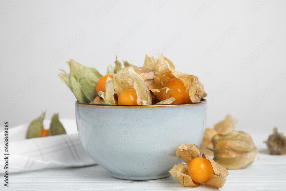 Ripe physalis fruits with dry husk on white wooden table Ripe physalis fruits with dry husk on white wooden table