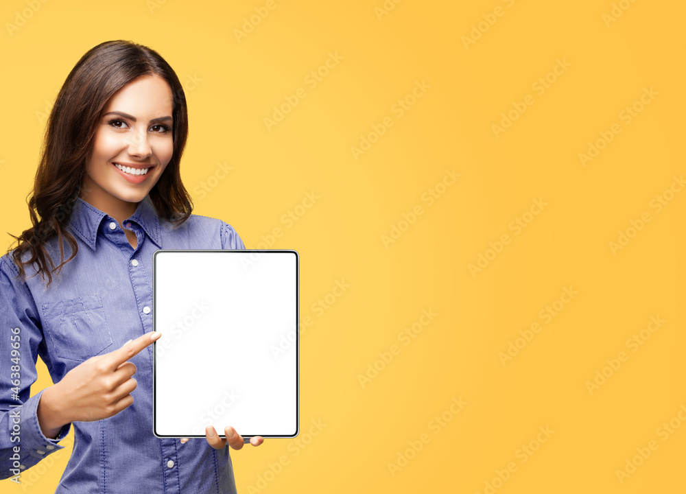 Portrait of happy smiling brunette businesswoman showing tablet pc with mock up monitor, copy space area for some text, advertising or slogan, over orange yellow color background. Business woman. Portrait of happy smiling brunette businesswoman showing tablet pc with mock up monitor, copy space area for some text, advertising or slogan, over orange yellow color background. Business woman.