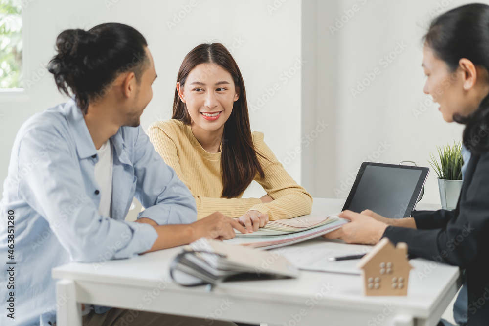Happy asian couple client, people choose color on palette chart for swatch, paint on wall for new home with designer woman at office desk. Material of interior design. Happy asian couple client, people choose color on palette chart for swatch, paint on wall for new home with designer woman at office desk. Material of interior design.
