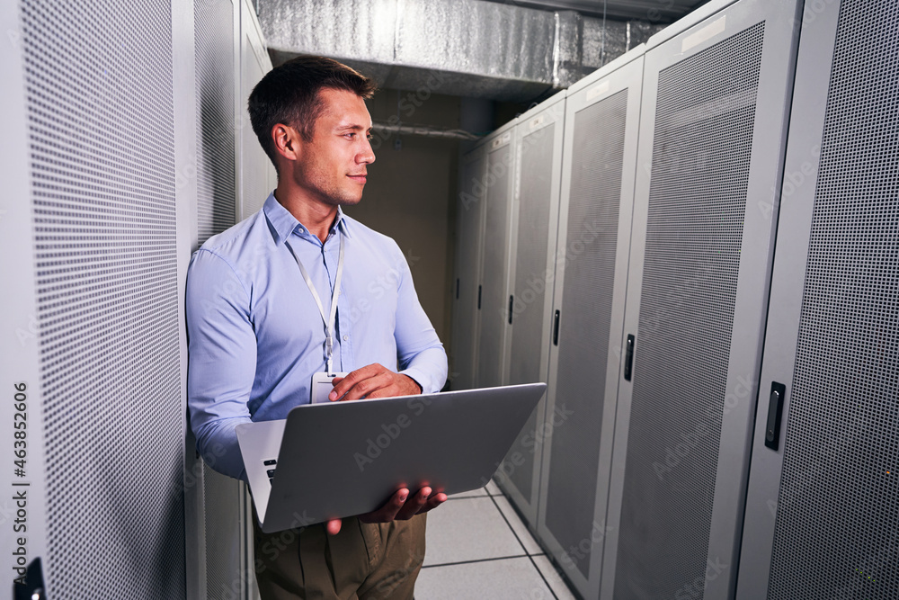Fototapeta premium Tranquil data center worker with laptop looking away