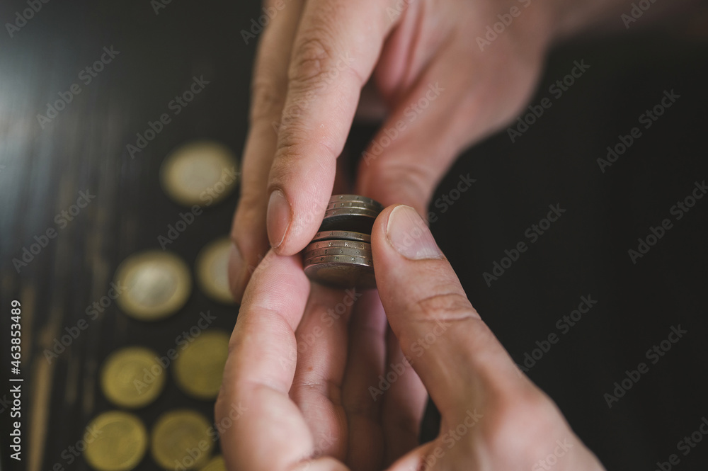 Fototapeta premium business man counting money. rich male hands holds and count coins of different euros on table