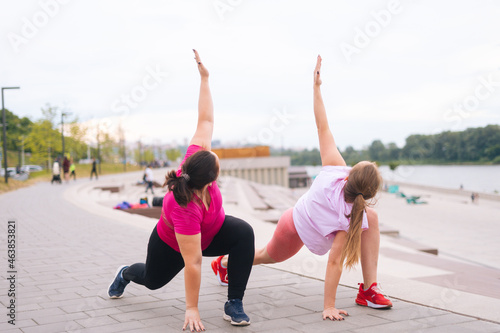 Front view of professional fitness female trainer have personal training with positive overweight young woman outdoor in summer morning. Instructor help overweight woman lose weight outside.