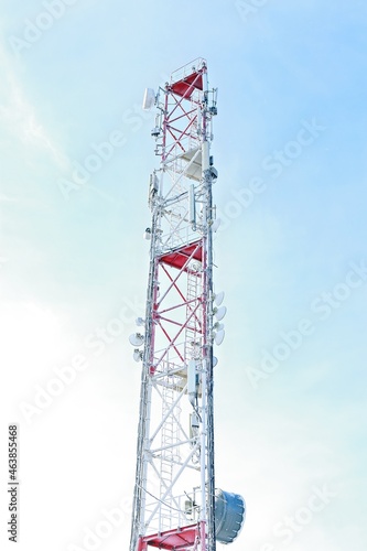 Telecommunications tower with many different antennas for transmitting TV and radio signals. Frozen Cellular Tower in the mountains. Winter industrial landscape. Bright sunlight. Vertical shot