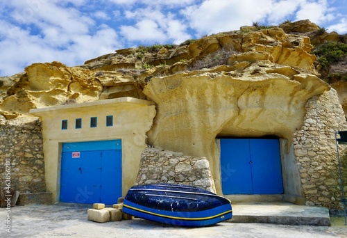 The fishing village of Dahlet Qorrot on the island of Gozo, Malta. Boathouses built in  the soft limestone cliff. and blue painted doors photo