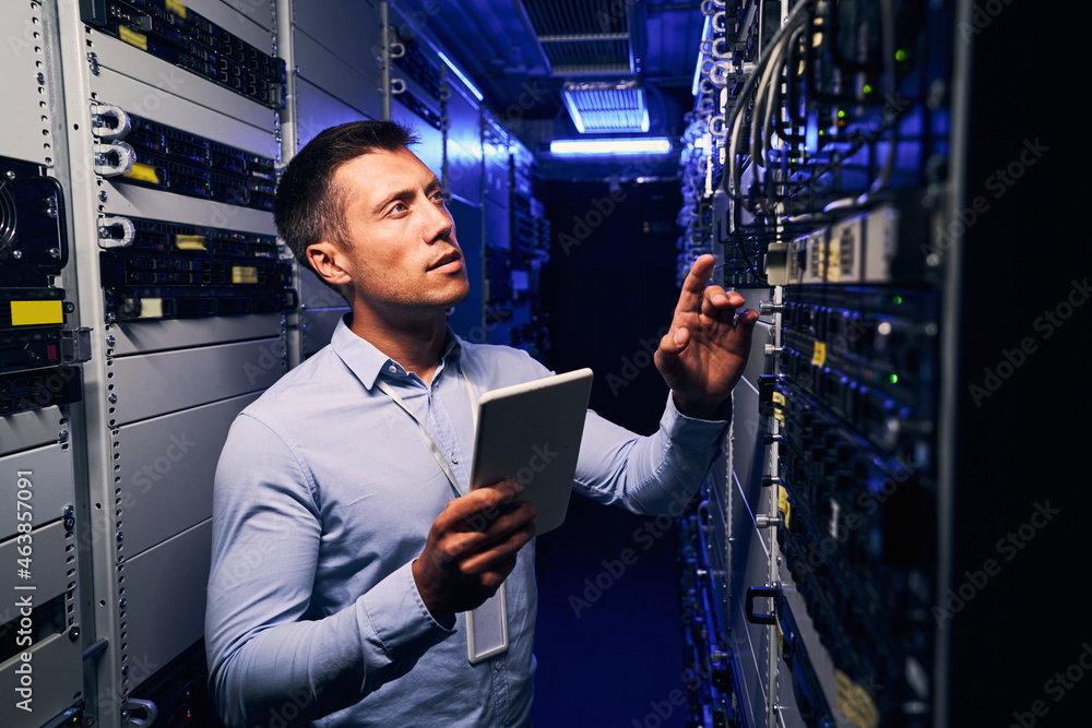 Fototapeta premium Employee inspecting hardware equipment in colocation center