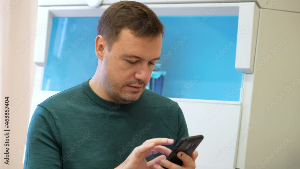 Chemistry lab researcher man using smartphone in biomedical laboratory. Scientist sitting in vintage style laboratory and typing text on phone. Happy scientist in room with laboratory box in UV light Chemistry lab researcher man using smartphone in biomedical laboratory. Scientist sitting in vintage style laboratory and typing text on phone. Happy scientist in room with laboratory box in UV light
