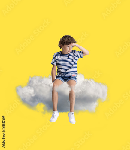 Creative collage with little preschool boy sitting on white cloud and flying at sky. Concept of childhood, dreams, fantasy