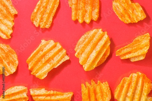 Ribbed potatoes snack with pepper on red background. Ridged potato chips on red background. Set of potato chips. Flat lay. Close-up