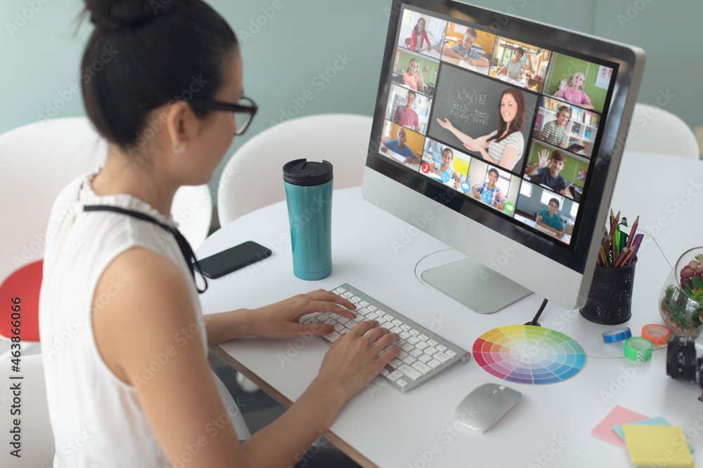 Caucasian girl using computer for video call, with diverse elementary school pupils on screen Caucasian girl using computer for video call, with diverse elementary school pupils on screen