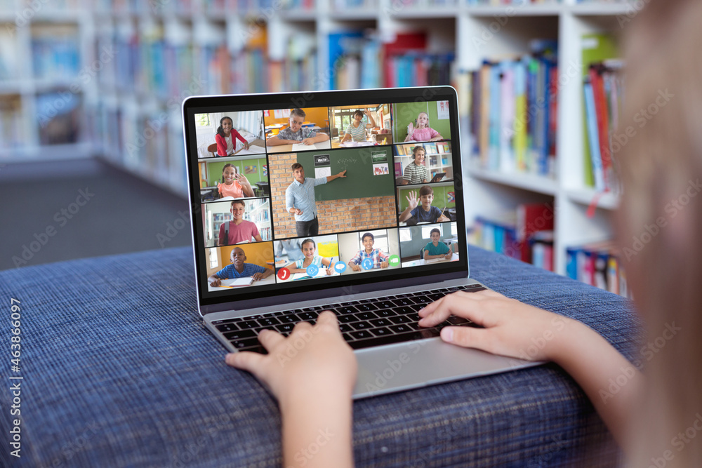 Caucasian girl using laptop for video call, with smiling diverse elementary school pupils on screen Caucasian girl using laptop for video call, with smiling diverse elementary school pupils on screen