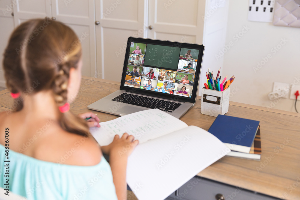 Caucasian girl using laptop for video call, with smiling diverse elementary school pupils on screen Caucasian girl using laptop for video call, with smiling diverse elementary school pupils on screen
