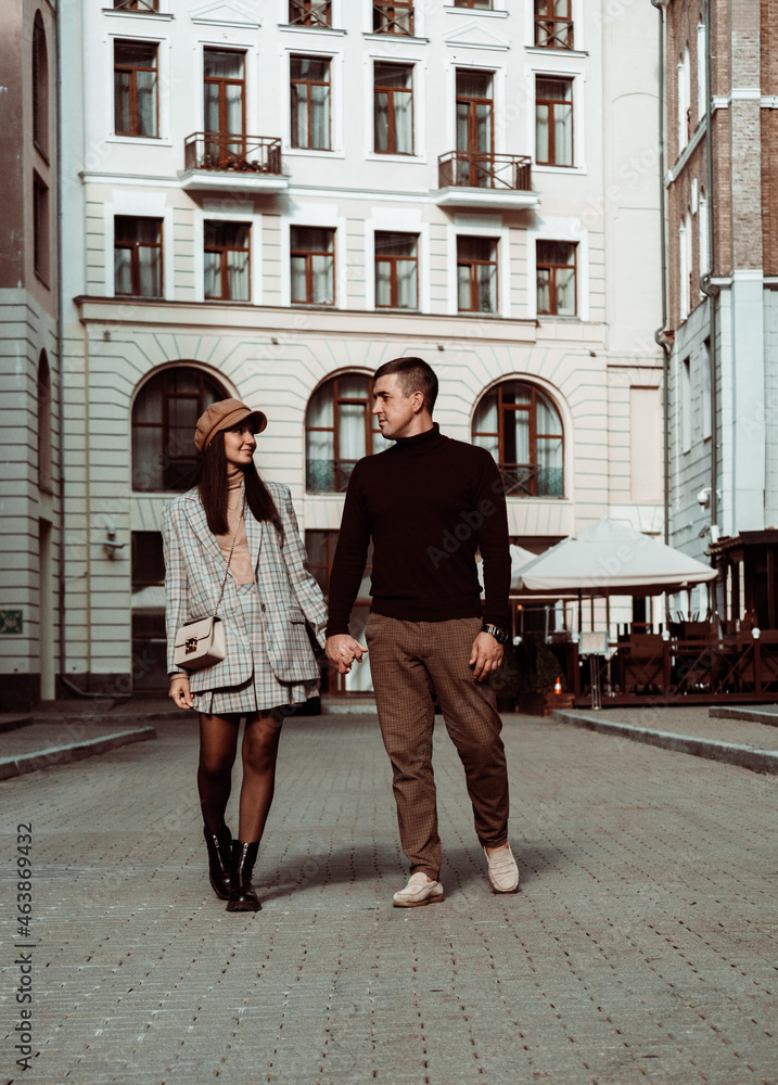 Candid portrait of fashionable couple. Man and woman watching to each other on background of city street. Autumn dating. Love and happiness.