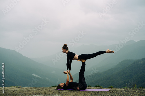 Man and Woman in Black Sport Clothes Doing Acroyoga on a Sea Beach
