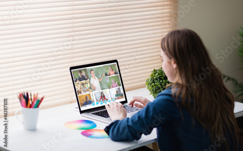 Caucasian woman using laptop for video call, with diverse elementary school pupils on screen