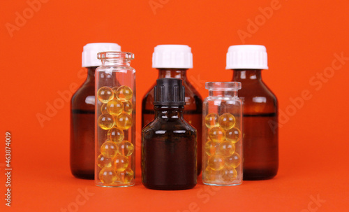 Glass bottles with medicines on orange background