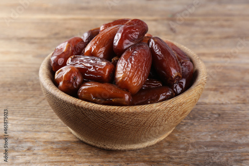 Sweet dried dates in bowl on wooden table, closeup