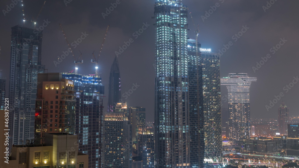 Cranes working on modern constraction site works of new skyscrapers night timelapse