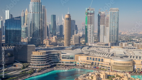 Skyscrapers rising above Dubai downtown timelapse, mall and fountain surrounded by modern buildings aerial top view
