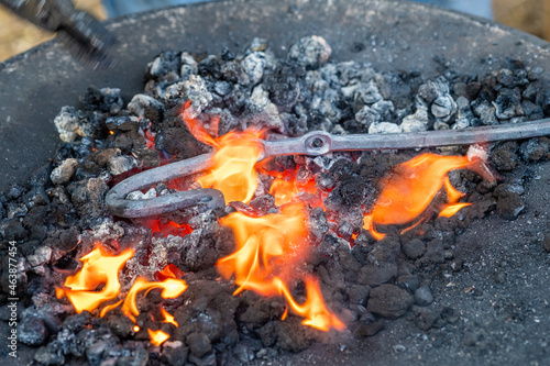 Close up of a piece of iron being heated in a coal fire by a blacksmith