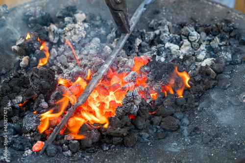 Close up of a piece of iron being heated in a coal fire by a blacksmith