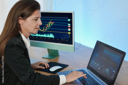 Mature trader woman working inside hedge fund office and studying stock market - Finance  investment and trading concept