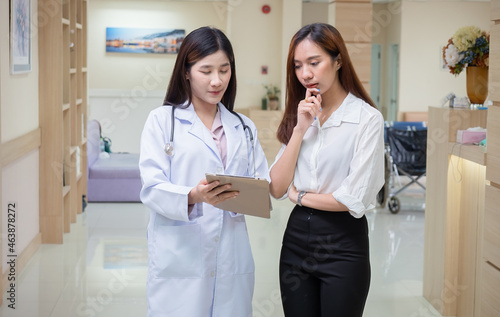 Asian female doctor explaining diagnosis to her female patient on a digital tablet in the hospital. Medicine and health care concept..