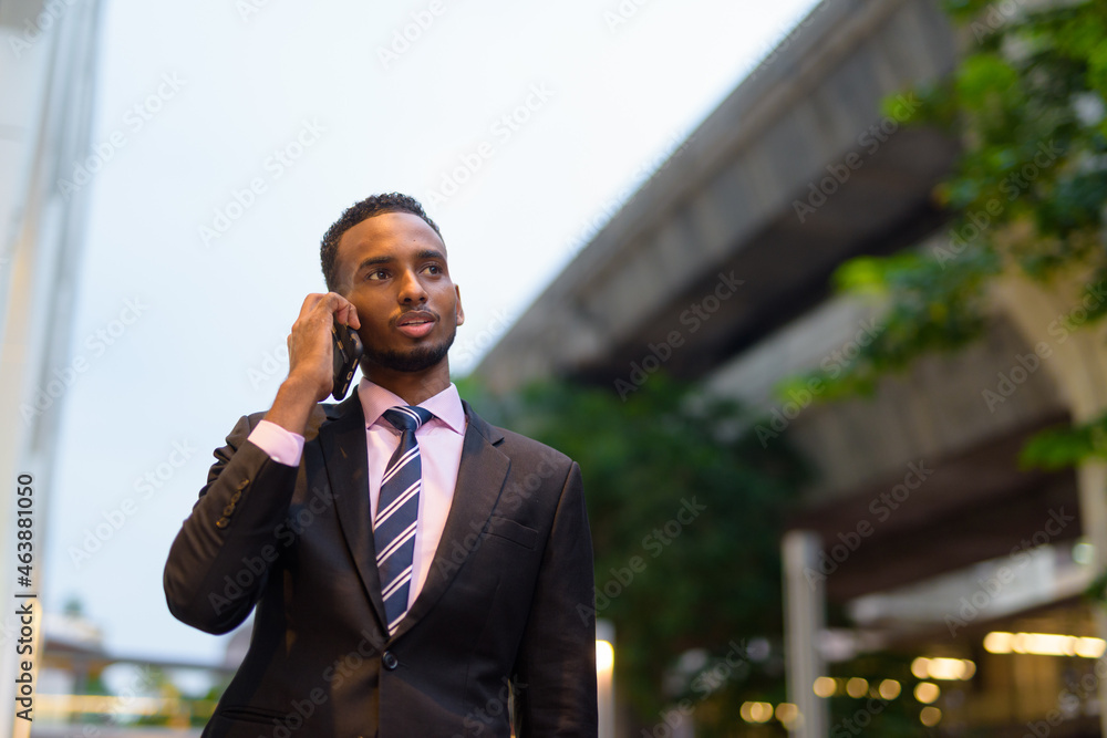 Young African businessman outdoors in city talking on mobile phone