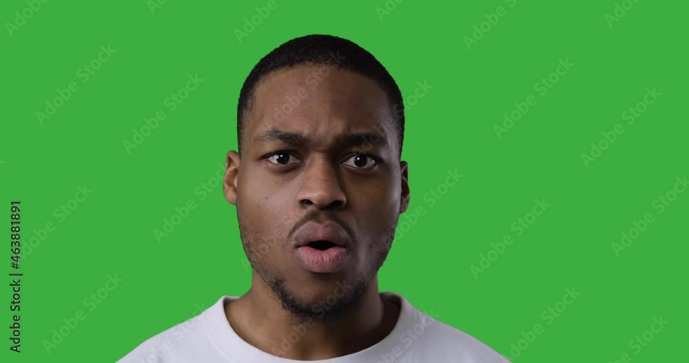 Shocked man shaking head in denial over green background Shocked man shaking head in denial over green background