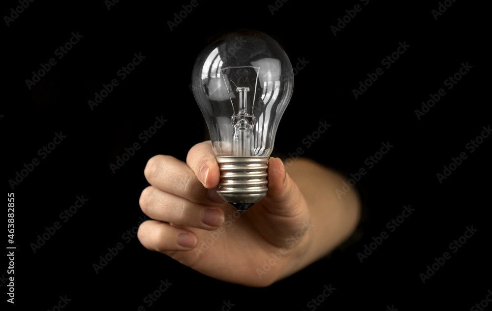 Light bulb in hand of woman in black background. New idea or inspiration concept Light bulb in hand of woman in black background. New idea or inspiration concept