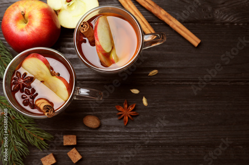 Aromatic hot mulled cider on black wooden table, flat lay. Space for text