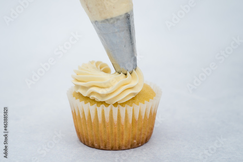 vanilla cupcake decorated with piping bag white vanilla cream 