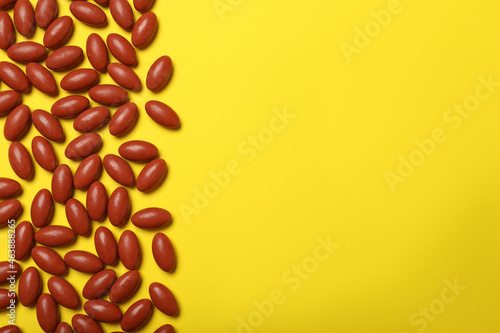 Many pills on yellow background, flat lay with space for text photo